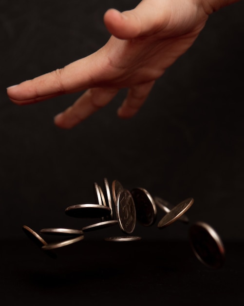 A hand reaching out to stop a pile of coins from tumbling over, signifying debt control and financial prudence.