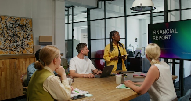 A diverse group of people attending a financial literacy workshop, with a presenter explaining concepts on a whiteboard. The atmosphere is engaged and positive, with attendees taking notes and asking questions.