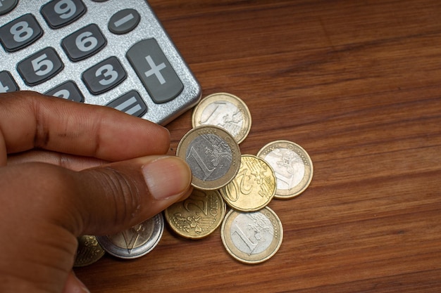 A person's hands holding a calculator and various denominations of Brazilian Real bills, symbolizing financial calculation and the impact of the minimum wage on personal finances.