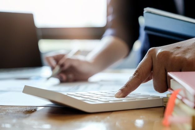 A close-up shot of a person's hands using a calculator and reviewing financial documents, emphasizing the meticulousness required when preparing income tax returns.