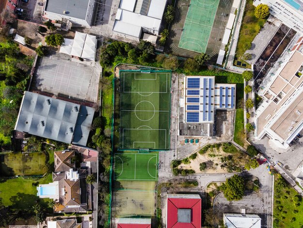 An aerial shot of a modern and well-equipped soccer training facility in Brazil, featuring multiple high-quality soccer fields, a modern gymnasium, and a dormitory for young athletes. The sky is clear and sunny, showcasing the vibrancy of the facility.