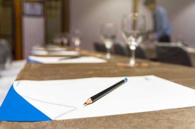 A close-up shot of a contract signing ceremony, with a pen hovering over the signature line and important people in business attire seated around the table.