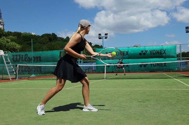 A tennis player performing a lunge exercise on a clay court, demonstrating strength and agility training. The player is focused and determined, with the clay court providing a traditional Brazilian tennis setting.