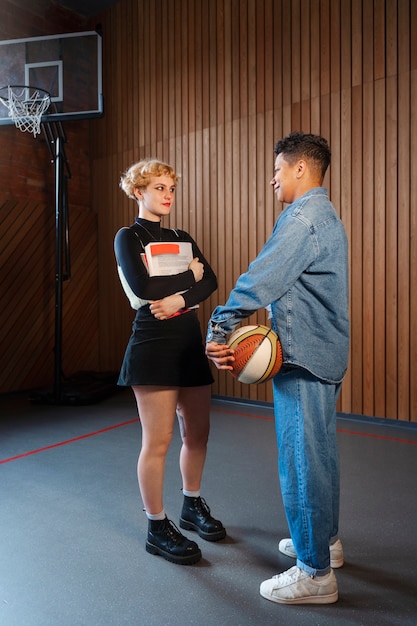 A coach is showing a young basketball player the correct way to hold a basketball before shooting. The background is a brightly lit indoor basketball court.