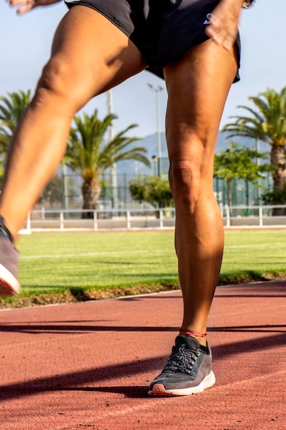 A close-up of a Brazilian athlete's legs, showing defined muscle tone, in motion during a speed training session on a running track.