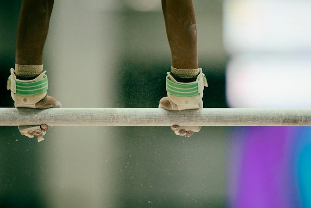 A close-up shot of a Brazilian gymnast's hands gripping the parallel bars, chalk visible, illustrating the strength and precision required.