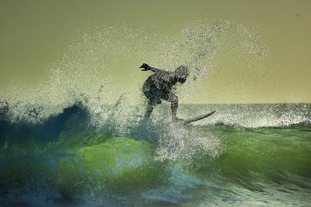 A surfer performing a powerful cutback maneuver on a wave during a surfing competition. The water is spraying behind the surfer, and the expression on their face shows focus and determination.