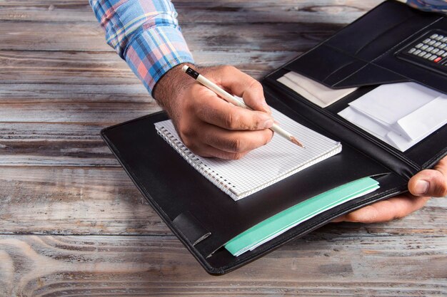 Close-up shot of hands carefully organizing important documents in a folder, with a pen and calculator nearby.
