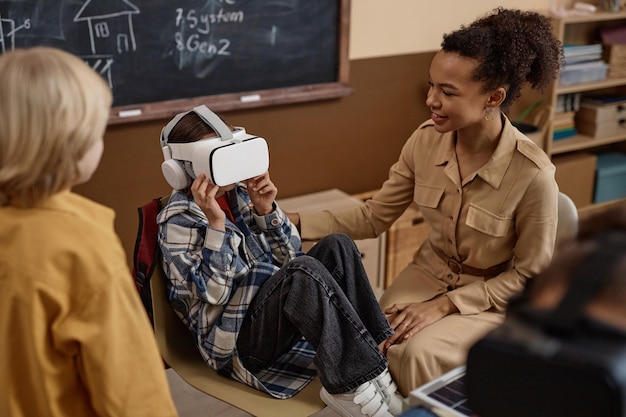 A teacher guiding a student through a virtual reality simulation in a science class, with other students observing and learning. The scene represents immersive learning and the use of advanced technology in education.