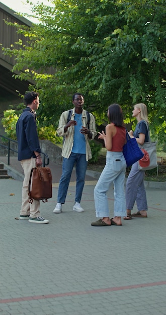 A diverse group of students walking across a university campus, engaging in conversations and carrying books. The backdrop includes well-maintained lawns, trees, and historic buildings, emphasizing the vibrant campus life and academic atmosphere.