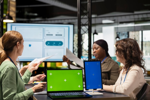 A person working on a laptop in a collaborative workspace, surrounded by digital devices and screens, highlighting technology proficiency.