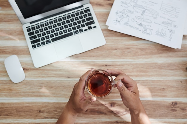 A close-up shot of hands typing on a laptop keyboard, with a cup of coffee and research papers scattered around, symbolizing the hard work and dedication required for graduate studies.