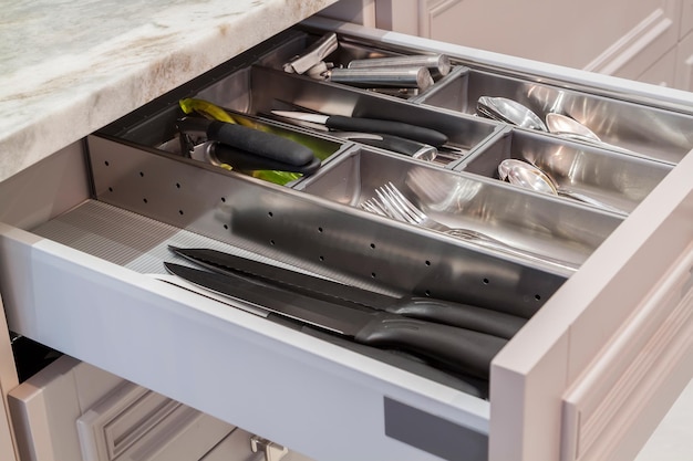 A close-up shot of a kitchen drawer with neatly stacked utensils, organized by type, using dividers to maximize space and prevent clutter.