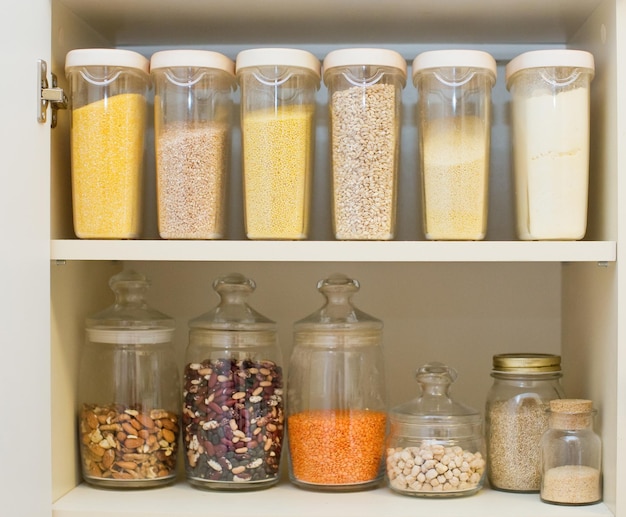 An organized pantry with clear containers holding various dry goods, labeled for easy identification, and shelves arranged to maximize vertical space.