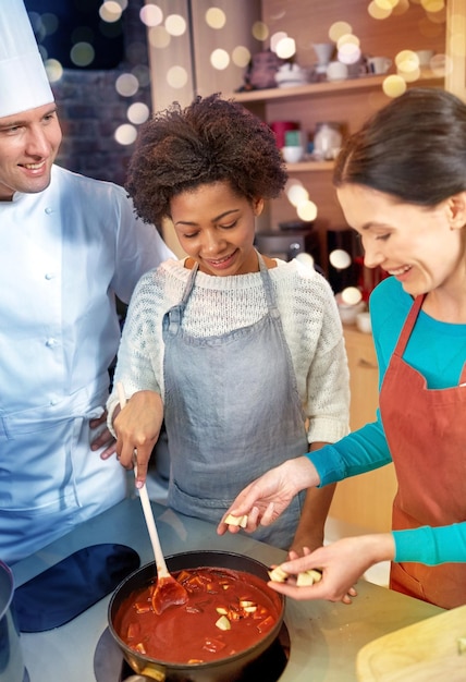 A group of tourists participating in a cooking class in Rio de Janeiro, learning how to prepare traditional Brazilian dishes like brigadeiro and pão de queijo, guided by a local chef.